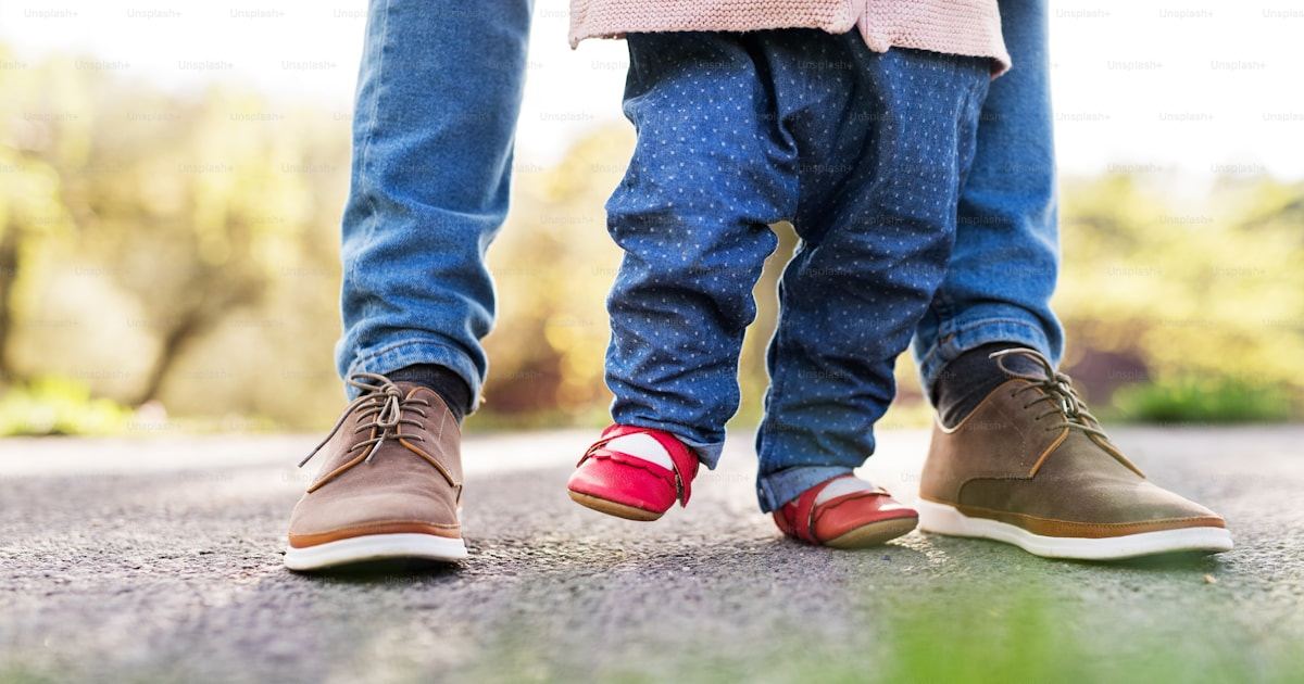 Toddler taking first steps outdoors while learning to walk