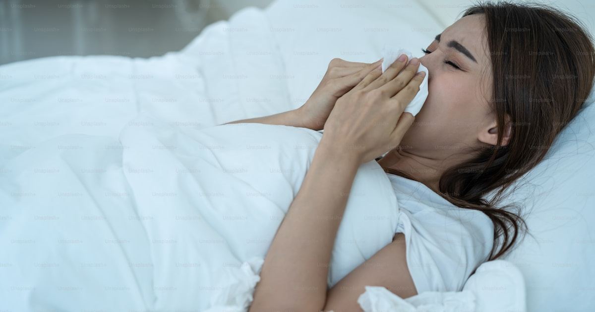 Woman blowing her nose in bed with persistent nasal congestion and sinus symptoms