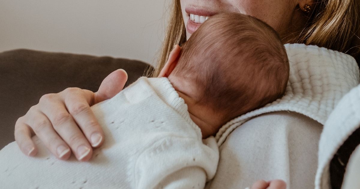 Mother holding her sleeping newborn baby close during the first weeks at home